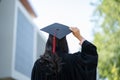 Graduation day, back view of Asian woman with graduation cap and coat holding diploma, success concept Royalty Free Stock Photo