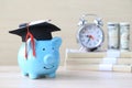 Graduation hat on blue piggy bank with stack of coins money and banknote on wooden background, Saving money for education concept Royalty Free Stock Photo