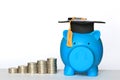 Graduation hat on blue piggy bank with stack of coins money on white background, Saving money for education concept