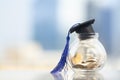 Graduation hat with blue tassel on top of glass jar or piggy bank