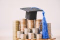 Graduation hat on coins money on white background. Saving money for education or scholarship concepts.