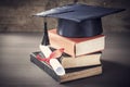 Graduation hat and diploma with book on table Royalty Free Stock Photo
