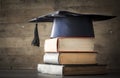 Graduation hat and diploma with book on table