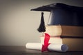 Graduation hat and diploma with book on table