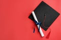 Graduation hat and diploma on red background, flat lay. Space for text Royalty Free Stock Photo