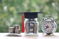 Graduation hat on the glass bottle and alarm clock on natural green background