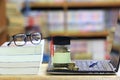 Graduation hat on the glass bottle on bookshelf in the library room background, Saving money for education concept