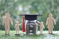 Graduation hat on the glass bottle with model family and stack of coins money on natural green background, Saving money for