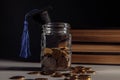 Graduation hat on jar with coins on a table. Scholarship money concept