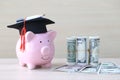 Graduation hat on Pink piggy bank with banknote on wooden background, Saving money for education concept Royalty Free Stock Photo