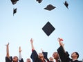 Graduation, students and graduate class throw caps in air feeling happy about education success at the ceremony