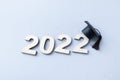 Graduation 2022 wearing graduate hat on wooden number 2022 on grey background with glitter