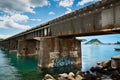 graffiti art on a rail bridge over clear water with a distant mountain under a partly cloudy sky. Royalty Free Stock Photo
