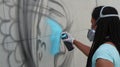 Graffiti artist spray paints a piece on a wall