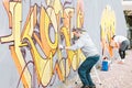 Graffiti artists painting colorful mural on a grey wall - Creative men performing drawing murals