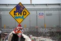 A graffiti covered End sign is adjacent to a homeless camp, trash, and train cars at 8100 Haskell Ave