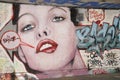 Graffiti depicting the face of a young woman with bright red lips.