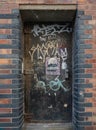 Graffiti on a old metal doorway on brick wall at Seel street