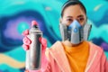 Graffiti painter in respirator mask pointing spray paint can to camera Royalty Free Stock Photo