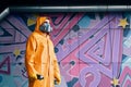 Graffiti painter in respirator mask standing near the wall with his paintings Royalty Free Stock Photo