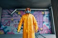 Graffiti painter in respirator mask standing near the wall with his paintings Royalty Free Stock Photo