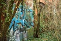 Graffiti on a rusty metal gate into overgrown building Royalty Free Stock Photo