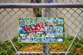 Graffiti on sign with messages on chain link fence for Trespassing Loitering Forbidden By Law