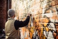 graffiti sprayer artist making intricate design on brick wall