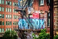 Graffiti and stairs on the side of a brick building seen from th