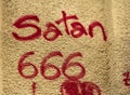 Graffiti on the wall. Satan 666 written with red paint on a wall