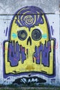 Graffiti on the wall in the street showing ghost in yellow and violet color.