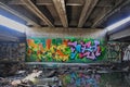 Graffiti on the wall under the old dilapidated underpass, water is flowing in the canal Royalty Free Stock Photo