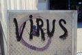 Graffiti writing saying "Virus" on metallic board in the street