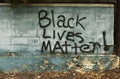 Grafitti message signs on cement wall by sidewalk. Black Lives Matter, Every Life, Stop the Violence.