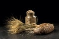 Grain bouquet, golden oats spikelets in jar on dark wooden table, buns and can filled with dried grains. Royalty Free Stock Photo