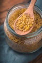 Grain bulgur in a glass jar and in a spoon partial blur