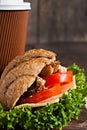 grain croissant sandwich and a cardboard cup of coffee on a dark Royalty Free Stock Photo