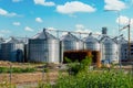 Grain elevator for processing and storage of grain is located in the sunflower field Royalty Free Stock Photo