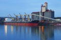 Grain elevators & cargo ship at dusk. Royalty Free Stock Photo