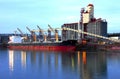Grain elevators & cargo ship at dusk. Royalty Free Stock Photo