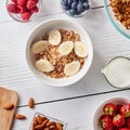 Healthy breakfast ingredients on a white woodwn background. Granola, nuts, berries, milk, banana in bowl , top view Royalty Free Stock Photo