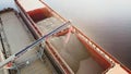 Grain loading in hold of bulk carrier ship with elevator crane closeup. Port grain elevator.