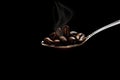 Grain roasted coffee spoon with smoke on black background. Royalty Free Stock Photo