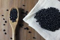 Grains black bean bag on side of wooden table, wooden spoon with black beans Royalty Free Stock Photo