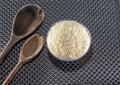 Grains of cereal rice on a dark background in a jar next to wooden spoon