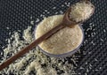 Grains of cereal rice on a dark background in a jar next to wooden spoon