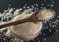 Grains of cereal rice on a dark background in a jar next to wooden spoon