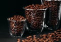 Grains of coffee in glass transparent cups with black background, dark coffee concept