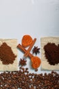 Grains of coffee and slices of dried oranges are scattered on the surface of the table. Cinnamon sticks and anise are also visible