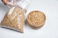 Grains of oats in a wooden bowl and a transparent bag on a white background Royalty Free Stock Photo